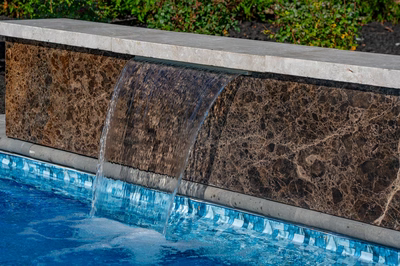 Formal B - Forrest Hills, MD - A water feature in a swimming pool surrounded by greenery