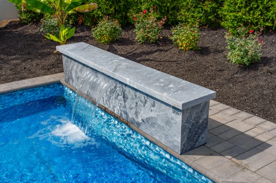 Formal G -  - A concrete bench with a waterfall in a swimming pool surrounded by plants and flowers