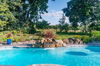 Franconia B - Malvern, PA - A swimming pool with a waterfall surrounded by lush greenery and colorful flowers