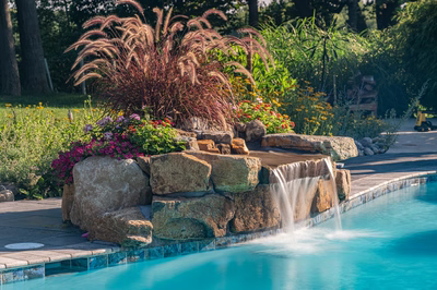 Franconia E - Malvern, PA - A swimming pool surrounded by lush greenery and colorful flowers, with a waterfall feature