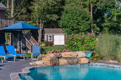 Franconia H - Malvern, PA - A backyard with a swimming pool surrounded by lush greenery and colorful flowers