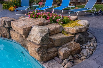 Franconia J - Malvern, PA - A decorative rock wall around a swimming pool with lounge chairs and flowers