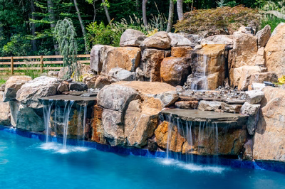 Gavarnie C - Monkton, MD - A large rock waterfall in the middle of a swimming pool surrounded by lush greenery