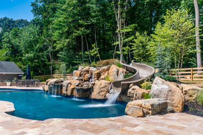 Gavarnie D - Monkton, MD - A swimming pool with a waterfall and a slide surrounded by lush greenery