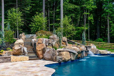 Gavarnie I - Monkton, MD - A large rock waterfall in the middle of a swimming pool surrounded by lush greenery