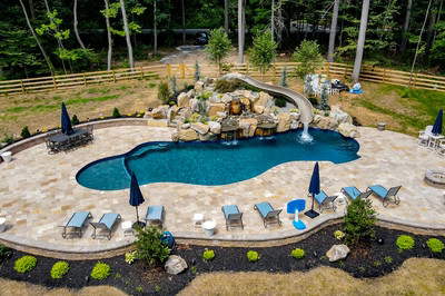 Gavarnie Q - Monkton, MD - A backyard with a pool and a waterfall surrounded by lush greenery
