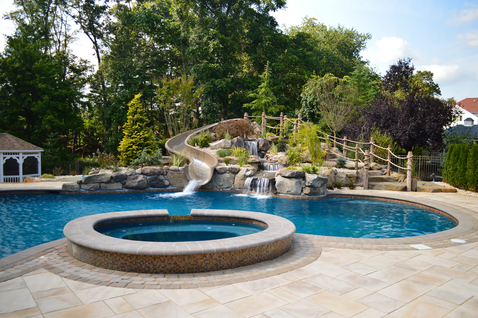 Natural stone boulder waterfall cascading into a freeform pool with lush surrounding landscaping