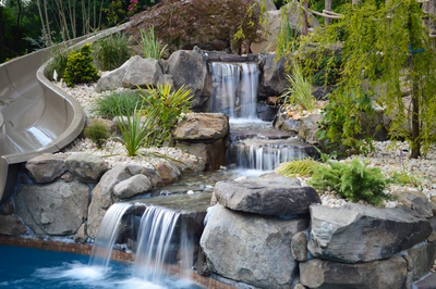 Genale D - Manalapan, NJ - A water feature in a backyard with a pool and a slide