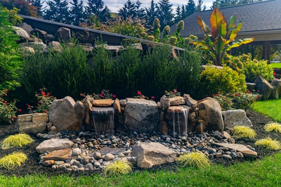 Genesis D - A rock garden with a waterfall surrounded by lush greenery and colorful flowers