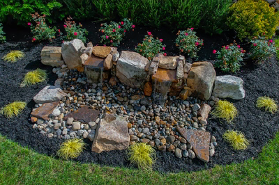 Genesis D - A rock garden with a small waterfall surrounded by flowers and grass