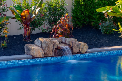 Genesis M -  - A pile of rocks next to a blue swimming pool
