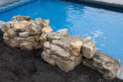 Genesis M -  - A blue swimming pool with rocks in the foreground