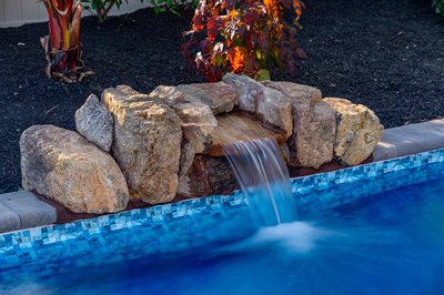Genesis M -  - A rock structure by a swimming pool surrounded by autumn leaves