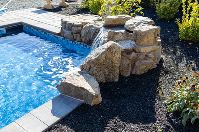 Genesis P - A swimming pool with a rock waterfall in the middle of it