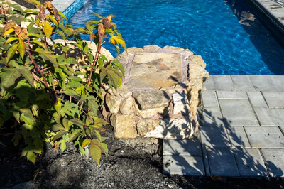 Genesis P - A stone bench next to a swimming pool with blue water.