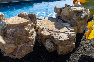 Genesis P - A group of stone stools sitting next to a swimming pool.
