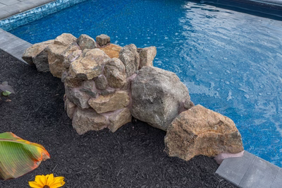 Genesis S -  - A rock structure by a swimming pool with water droplets on it