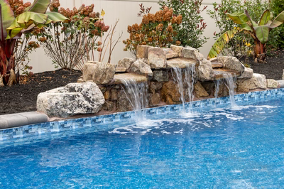 Genesis T -  - A swimming pool with a waterfall feature surrounded by tropical plants