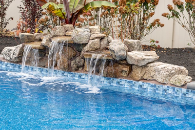 Genesis T -  - A swimming pool with a waterfall feature surrounded by plants and rocks