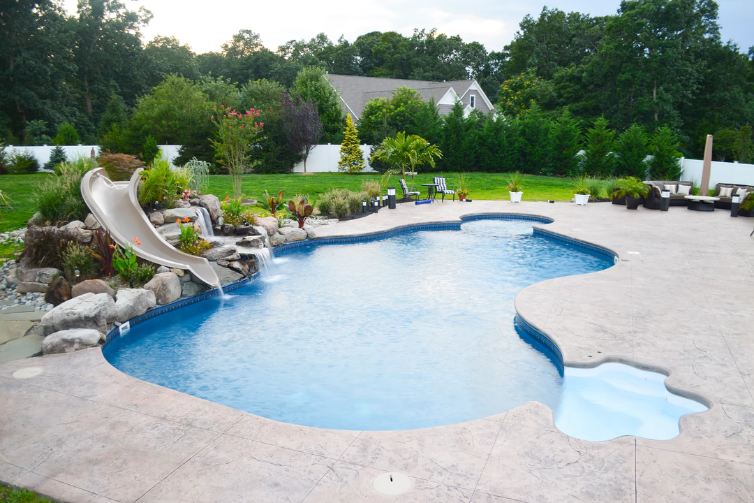 George M - Toms River, NJ - A swimming pool with a waterfall and a slide in a backyard setting