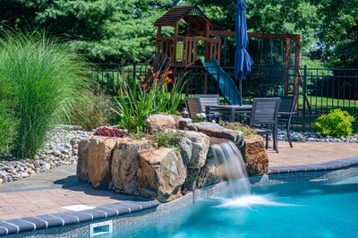 Georgiana D - Hillsborough, NJ - A backyard with a pool, a play structure, and a waterfall