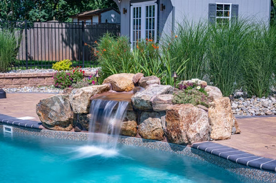 Georgiana F - Hillsborough, NJ - A small waterfall in the middle of a swimming pool surrounded by plants and flowers