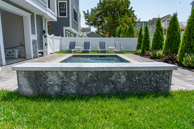 Gibbs C - Avalon, NJ - A backyard with a stone bench and a hot tub surrounded by lush green grass