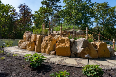 Gikira G - Bethlehem, PA - A large rock wall with a wooden fence in a park setting