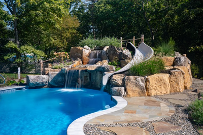 Gikira I - Bethlehem, PA - A swimming pool with a waterfall and a slide in a backyard setting