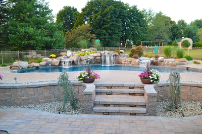 Ginga B - Ringoes, NJ - A backyard with a swimming pool surrounded by lush greenery and flowers.