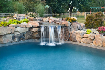 Ginga C - Ringoes, NJ - A swimming pool with a waterfall in the middle surrounded by rocks and plants
