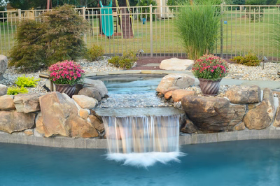 Ginga F - Ringoes, NJ - A backyard with a pool and a water feature surrounded by rocks and plants