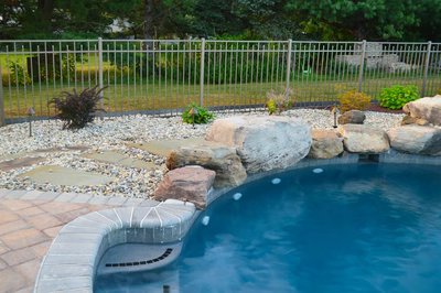 Ginga J - Ringoes, NJ - A swimming pool with rocks and pebbles around it, surrounded by a fence.