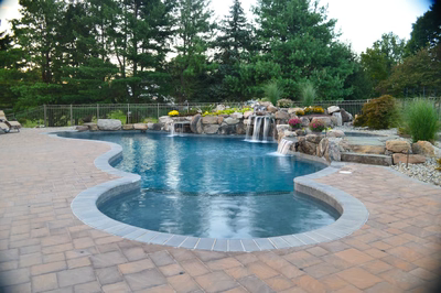 Ginga K - Ringoes, NJ - A swimming pool surrounded by lush greenery and a waterfall.