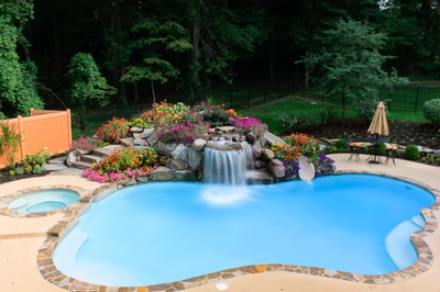 Gorge F - Huntington Valley, PA - A swimming pool with a waterfall surrounded by colorful flowers and greenery