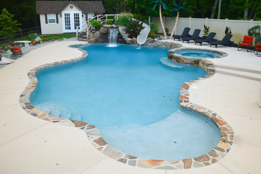 Grassie F - Mullica Hill, NJ - A swimming pool with a waterfall and a stone border around it