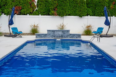 Haifoss J - Sicklerville, NJ - A blue swimming pool surrounded by a white fence and lush green hedges
