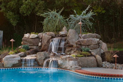 Harvard D - Sewell, NJ - A swimming pool with a waterfall in the middle surrounded by rocks and plants