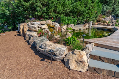 Havasu C - Manasquan, NJ - A serene garden with a wooden walkway leading to a small pond surrounded by rocks and plants
