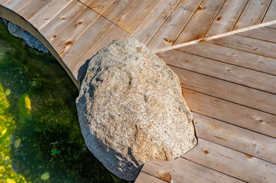 Havasu K - Manasquan, NJ - A large rock sitting on top of a wooden deck next to a small pond.