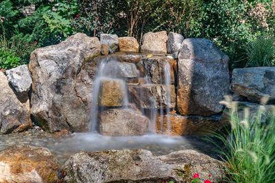 Havasu R - Manasquan, NJ - A small waterfall surrounded by large rocks and greenery in a garden setting