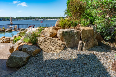 Havasu S - Manasquan, NJ - A rocky shoreline with a view of a body of water and trees in the background