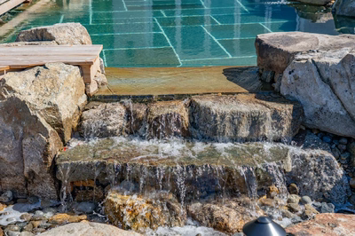 Havasu Y - Manasquan, NJ - A small waterfall in a rocky area next to a swimming pool.