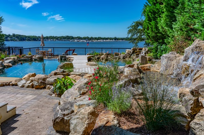 Havasu Z - Manasquan, NJ - A scenic view of a lake with a wooden walkway leading to a water feature surrounded by rocks and flowers