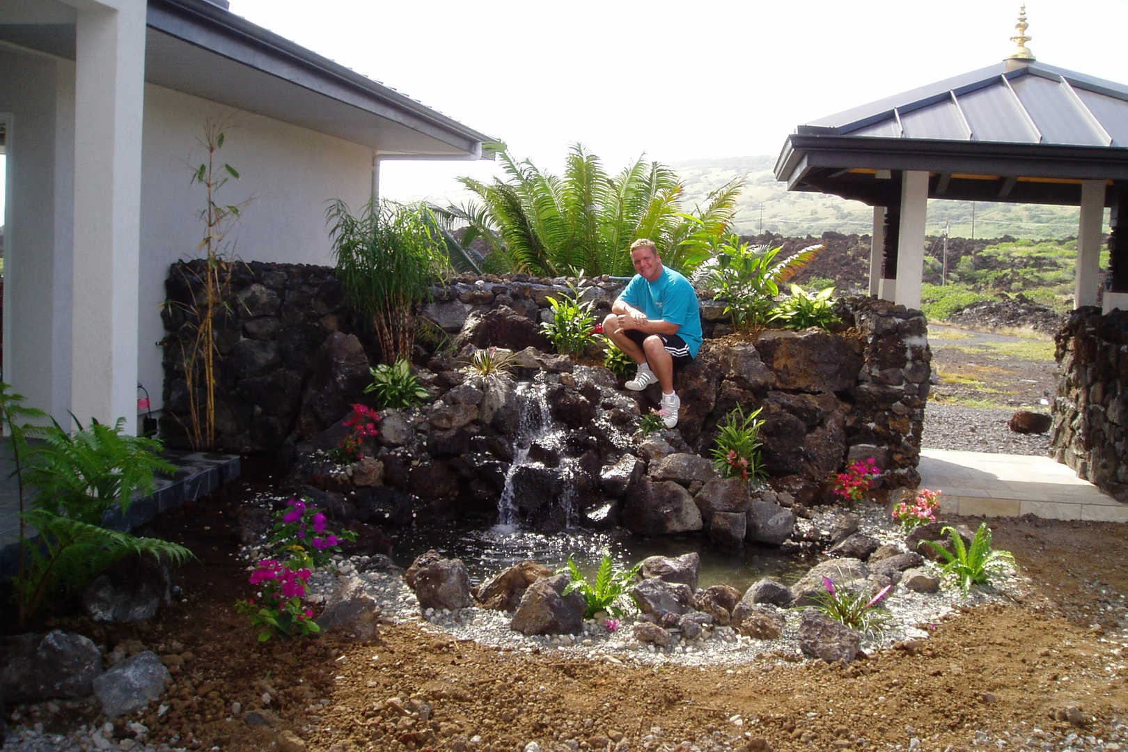 Natural stone boulder waterfall cascading into a pond with lush tropical landscaping