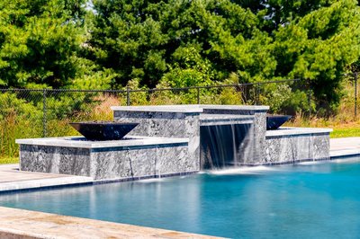 Haymeadow B - Mullica Hill, NJ - A swimming pool with a waterfall feature in the middle surrounded by lush green trees