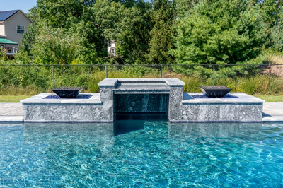 Haymeadow H - Mullica Hill, NJ - A swimming pool with a waterfall feature and fire pits in the middle of it