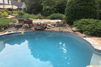 Hemlock C - East Petersburg, PA - A clear blue swimming pool surrounded by lush greenery and rocks.