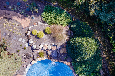 Hemlock L - East Petersburg, PA - A bird's eye view of a backyard with a swimming pool surrounded by greenery and rocks