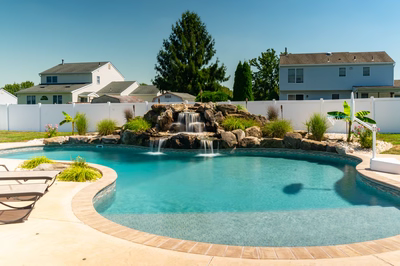 Hinemoa B - Turnersville, NJ - A backyard with a swimming pool and a waterfall feature